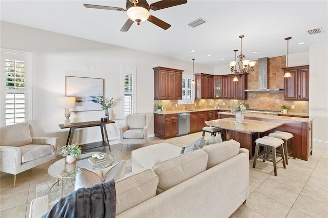 tiled living room featuring ceiling fan with notable chandelier, a healthy amount of sunlight, and sink