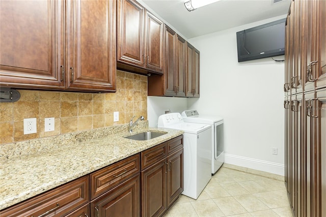 washroom with cabinets, light tile patterned floors, washing machine and clothes dryer, and sink