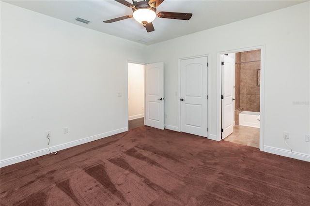 unfurnished bedroom featuring dark colored carpet, ensuite bathroom, and ceiling fan