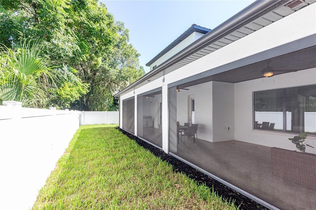 view of yard featuring a sunroom and ceiling fan