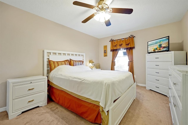 bedroom with ceiling fan, light carpet, and a textured ceiling