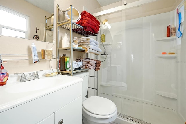 bathroom featuring a shower with door, vanity, a textured ceiling, and toilet