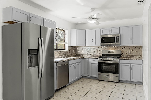 kitchen featuring decorative backsplash, gray cabinetry, stainless steel appliances, ceiling fan, and light tile patterned flooring