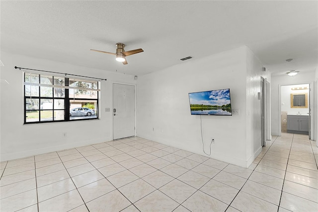 unfurnished room with ceiling fan, sink, light tile patterned flooring, and a textured ceiling