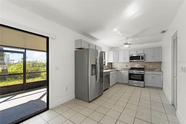 kitchen with gray cabinetry, ceiling fan, decorative backsplash, light tile patterned floors, and appliances with stainless steel finishes