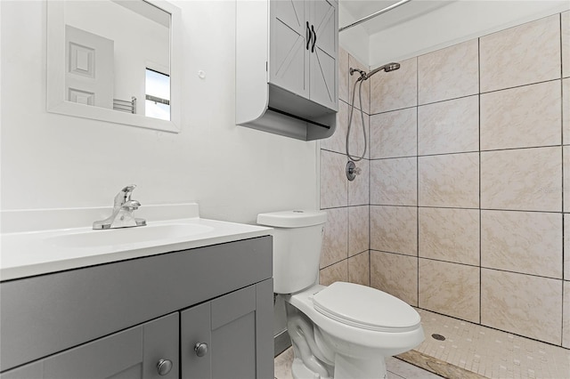 bathroom with tiled shower, vanity, and toilet