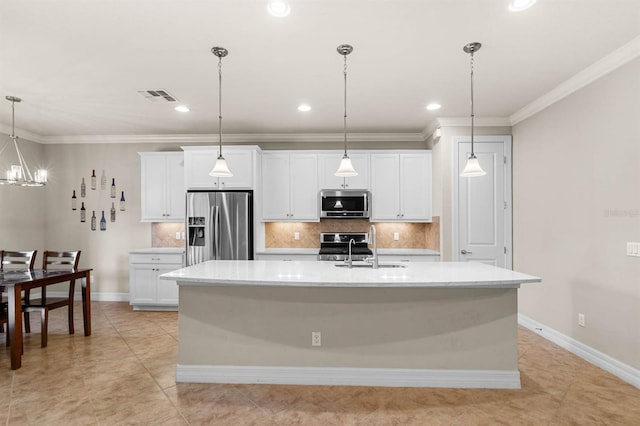 kitchen with white cabinets, decorative light fixtures, stainless steel appliances, and an island with sink