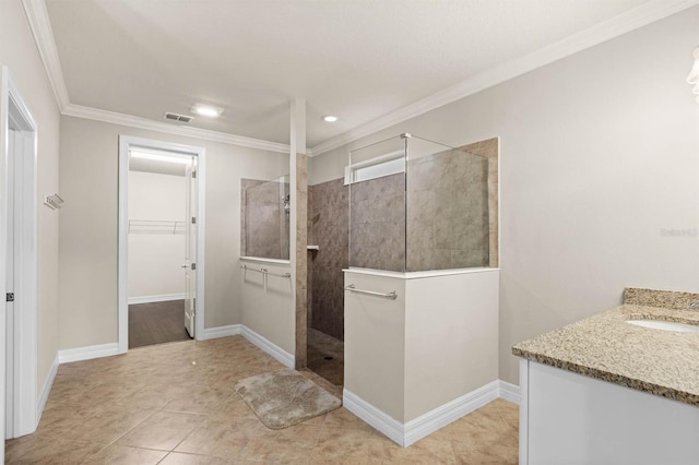 bathroom featuring tile patterned flooring, vanity, ornamental molding, and tiled shower