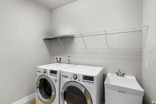 washroom with washing machine and clothes dryer, sink, and a textured ceiling