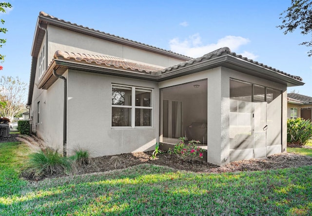 view of side of home featuring a lawn and a sunroom