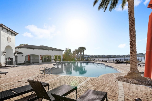 view of pool with a water view and a patio area