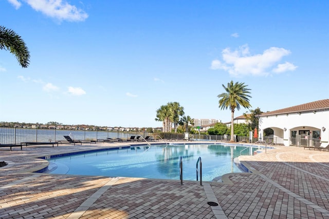 view of pool featuring a water view and a patio