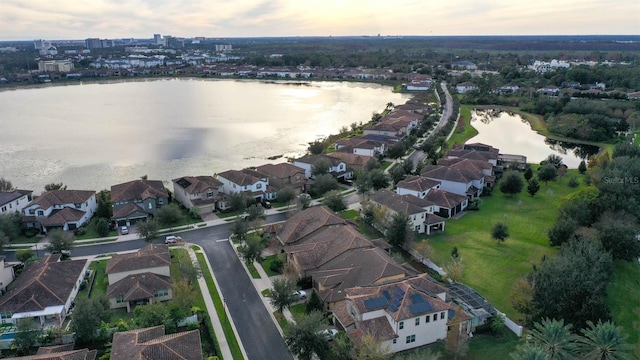 aerial view at dusk featuring a water view