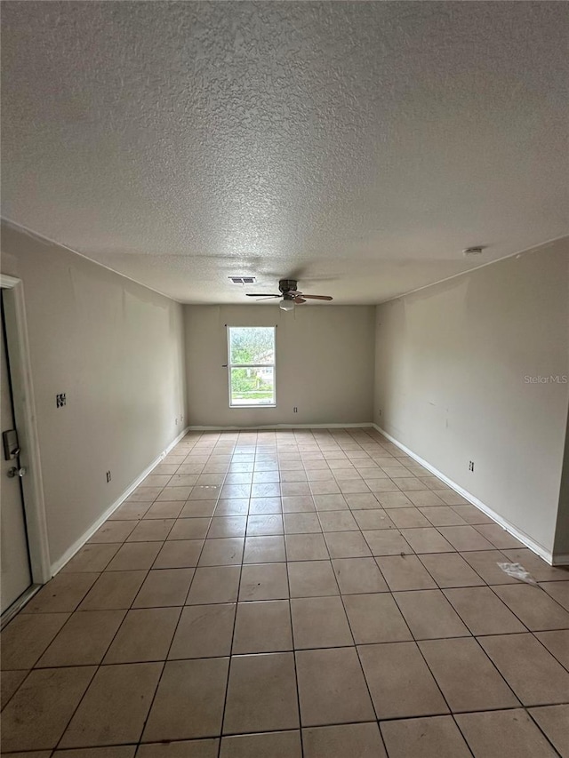 tiled empty room featuring a textured ceiling and ceiling fan