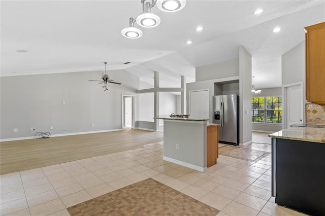 kitchen featuring ceiling fan with notable chandelier, vaulted ceiling, light stone countertops, light tile patterned floors, and stainless steel fridge with ice dispenser