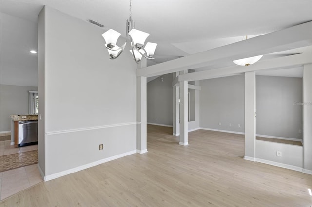 empty room featuring a chandelier, light hardwood / wood-style floors, and lofted ceiling