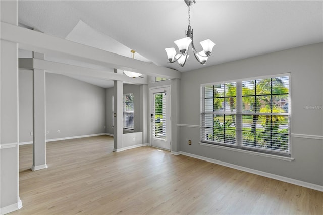 unfurnished room with light wood-type flooring, vaulted ceiling, and an inviting chandelier