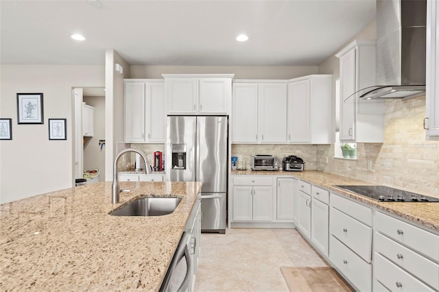 kitchen featuring appliances with stainless steel finishes, light stone counters, wall chimney exhaust hood, sink, and white cabinets