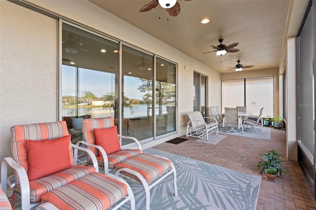 sunroom / solarium featuring ceiling fan and a water view