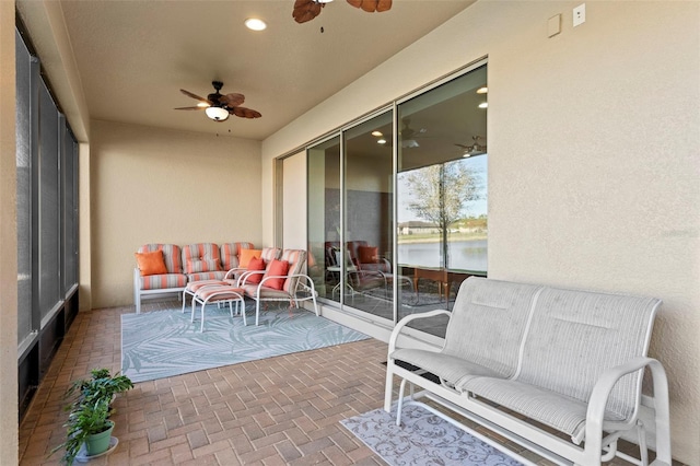 sunroom featuring ceiling fan and a water view