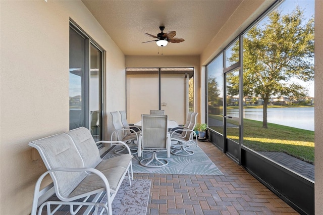 sunroom / solarium featuring a water view and ceiling fan