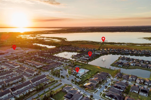 aerial view at dusk featuring a water view