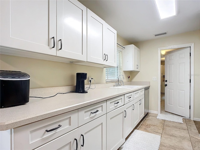 kitchen with light tile patterned floors, white cabinetry, stainless steel dishwasher, and sink