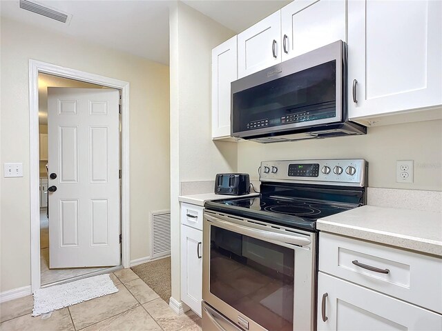 kitchen with white cabinets, light tile patterned floors, and stainless steel appliances