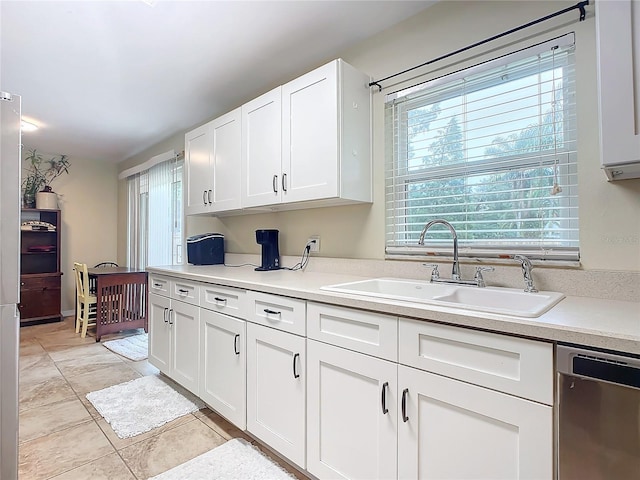 kitchen with dishwasher, sink, white cabinets, and light tile patterned flooring