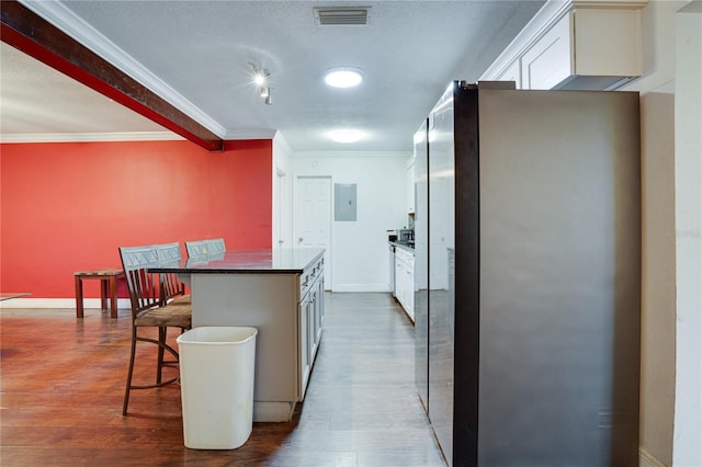 kitchen with white cabinets, stainless steel refrigerator, a breakfast bar, and a center island