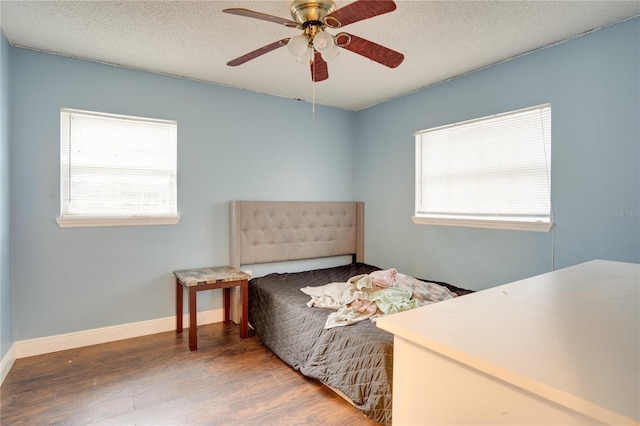 bedroom with ceiling fan, wood-type flooring, and a textured ceiling