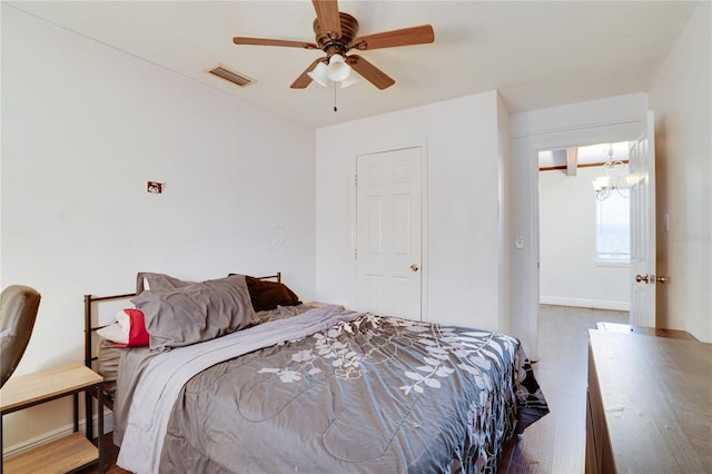 bedroom featuring ceiling fan with notable chandelier and light hardwood / wood-style flooring