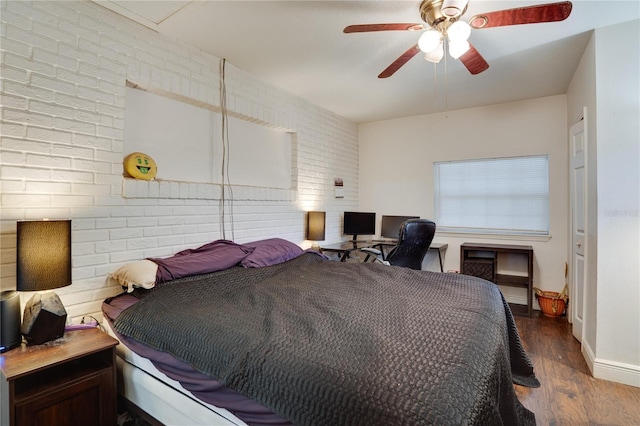 bedroom with ceiling fan, brick wall, and dark hardwood / wood-style floors