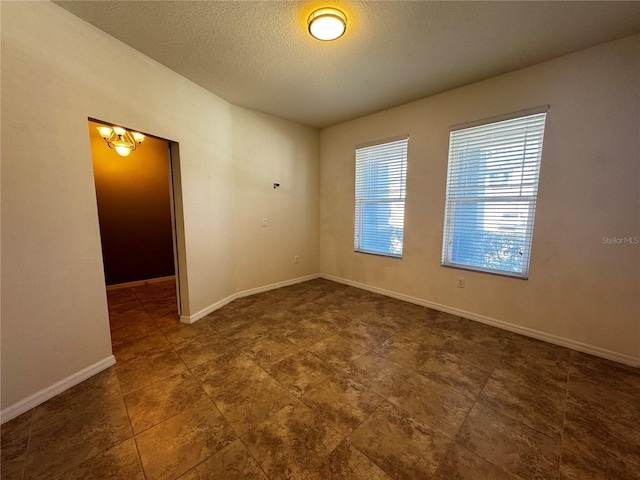 1570 Fox Grape Loop, Lutz, FL 33558 - unfurnished room with baseboards, a textured ceiling, and a notable chandelier