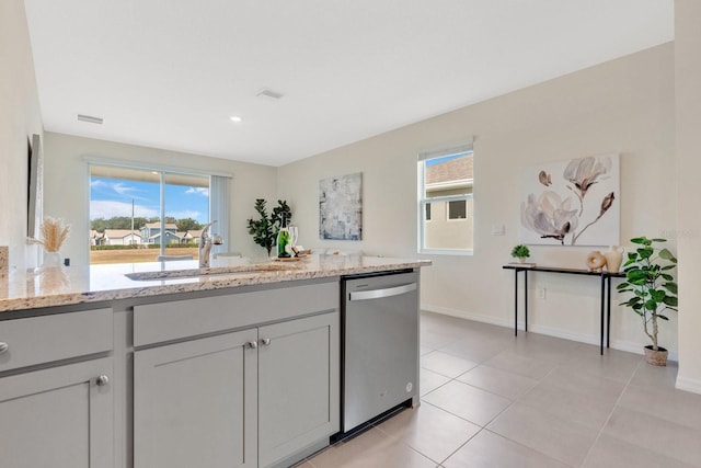 kitchen with stainless steel dishwasher, light tile patterned flooring, light stone countertops, and sink