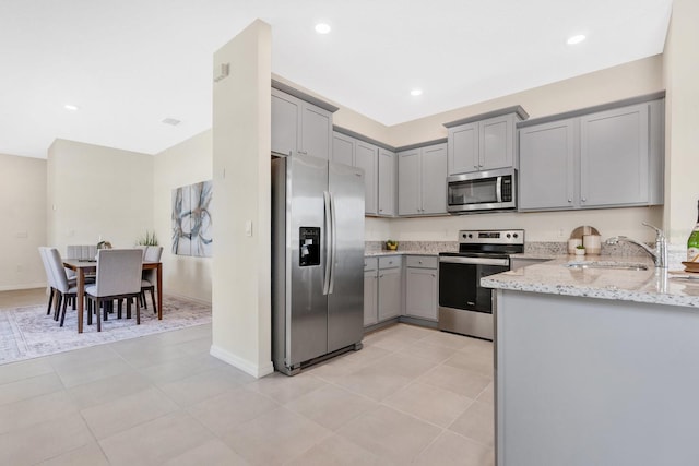 kitchen featuring gray cabinets, light stone counters, sink, and stainless steel appliances