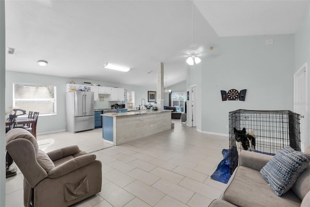 tiled living room with vaulted ceiling, ceiling fan, and sink