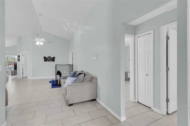 living room featuring ceiling fan, light tile patterned floors, and vaulted ceiling