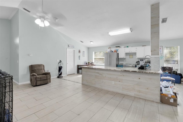 kitchen featuring ceiling fan, light stone counters, vaulted ceiling, white cabinets, and appliances with stainless steel finishes