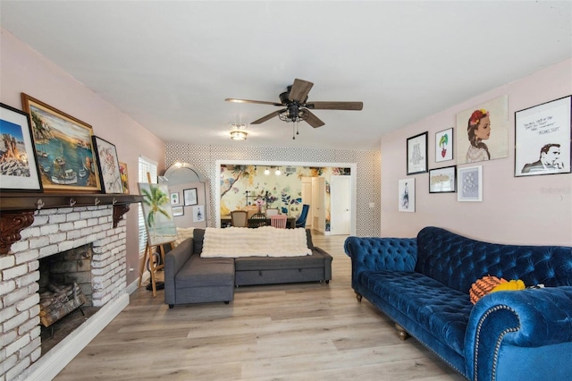 living room with a fireplace, light wood-type flooring, and ceiling fan