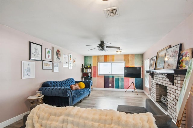 living room featuring ceiling fan, light wood-type flooring, and a fireplace