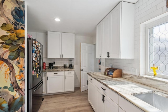 kitchen with white cabinetry, stainless steel refrigerator, tasteful backsplash, and plenty of natural light