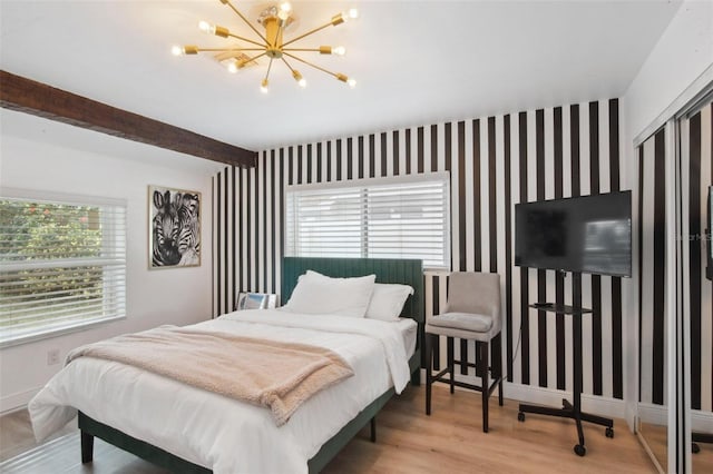 bedroom featuring beam ceiling, multiple windows, light hardwood / wood-style flooring, and a chandelier