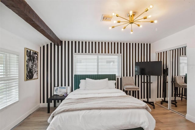 bedroom featuring beamed ceiling, a chandelier, and light hardwood / wood-style floors