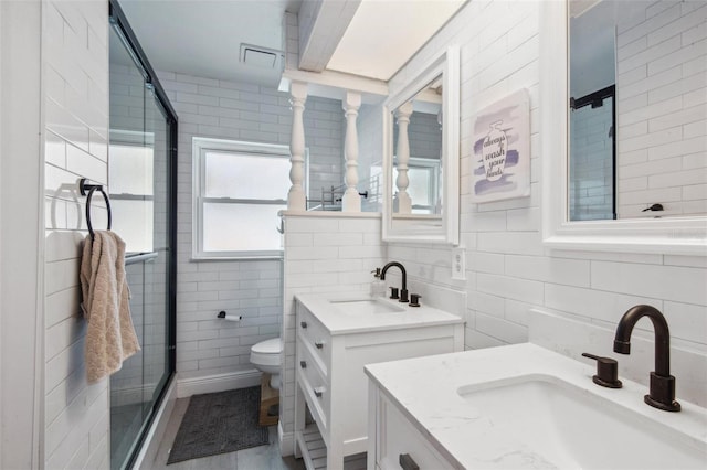 bathroom featuring decorative backsplash, vanity, tile walls, and walk in shower