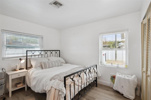 bedroom with multiple windows, a closet, and light wood-type flooring