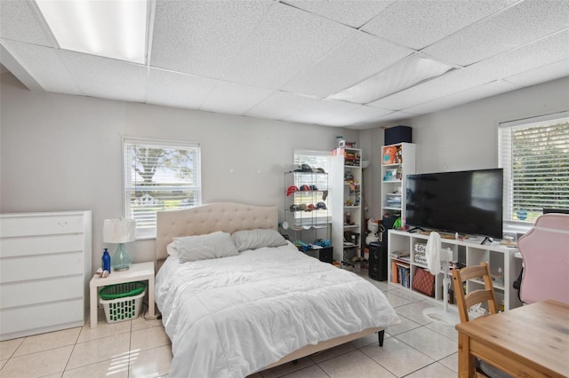 tiled bedroom with a paneled ceiling and multiple windows