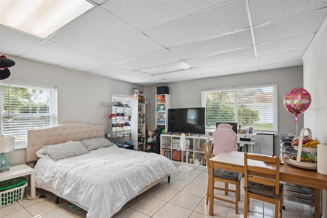 tiled bedroom with a drop ceiling and multiple windows