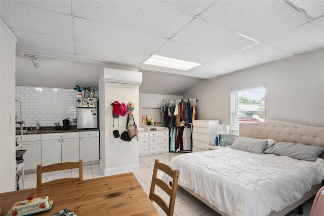 bedroom featuring a wall mounted air conditioner, a paneled ceiling, and light tile patterned flooring