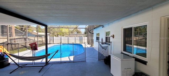 view of swimming pool featuring glass enclosure and a patio area